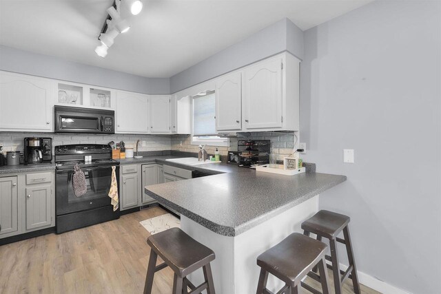 kitchen with a breakfast bar, black appliances, and tasteful backsplash