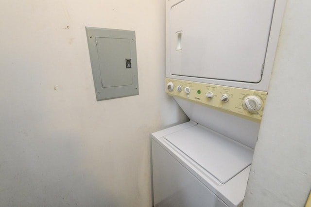 clothes washing area with stacked washer / drying machine, electric panel, and laundry area