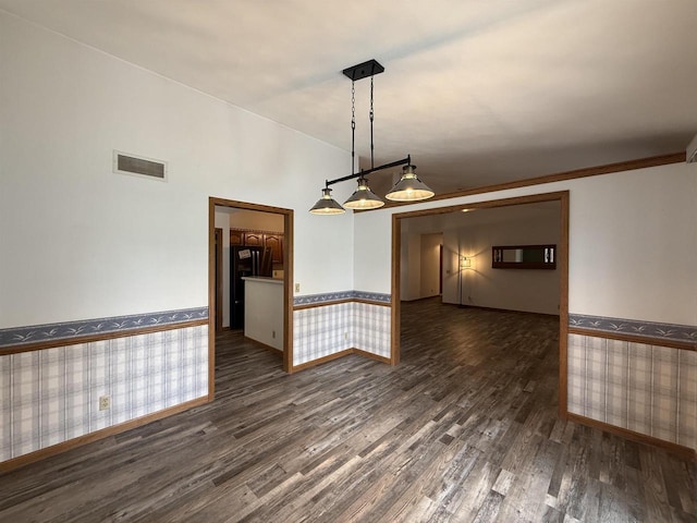 empty room featuring a wainscoted wall, wallpapered walls, wood finished floors, and visible vents