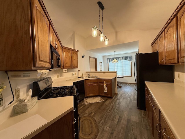 kitchen with a sink, light countertops, a peninsula, dark wood-style floors, and black appliances