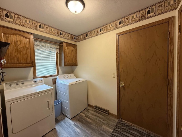 laundry area featuring cabinet space, baseboards, wood finished floors, visible vents, and washing machine and dryer