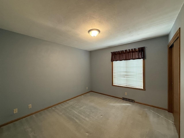 unfurnished bedroom with carpet flooring, baseboards, visible vents, and a closet