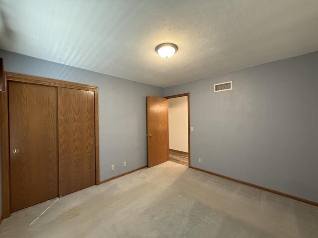 unfurnished bedroom featuring visible vents, carpet flooring, baseboards, and a closet