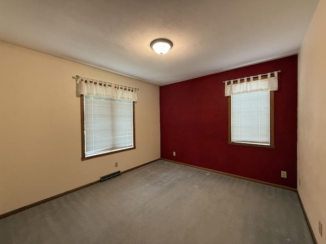 unfurnished room featuring baseboards, carpet flooring, and visible vents