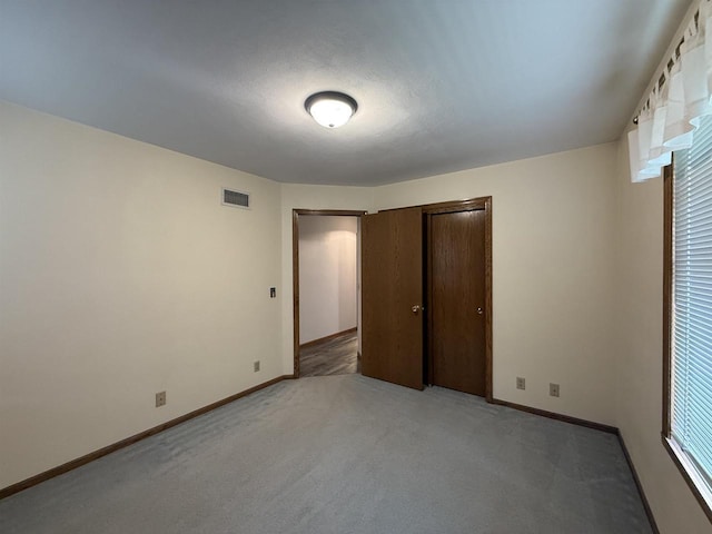 unfurnished bedroom with baseboards, a closet, visible vents, and light carpet