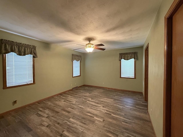 empty room with a ceiling fan, visible vents, a healthy amount of sunlight, and wood finished floors