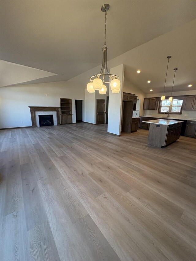 1354 Shelby Ln, De Pere, WI 54115 - unfurnished living room featuring recessed lighting, light wood finished floors, vaulted ceiling, a sink, and a fireplace
