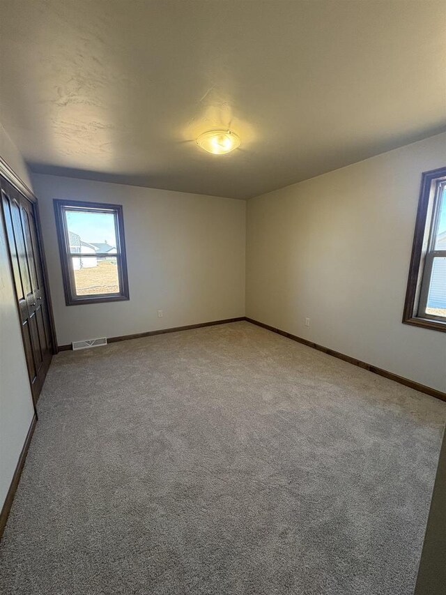 1354 Shelby Ln, De Pere, WI 54115 - spare room with a wealth of natural light, visible vents, and light carpet