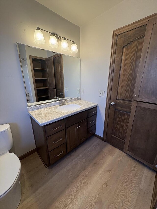 1354 Shelby Ln, De Pere, WI 54115 - bathroom with toilet, vanity, wood finished floors, and baseboards