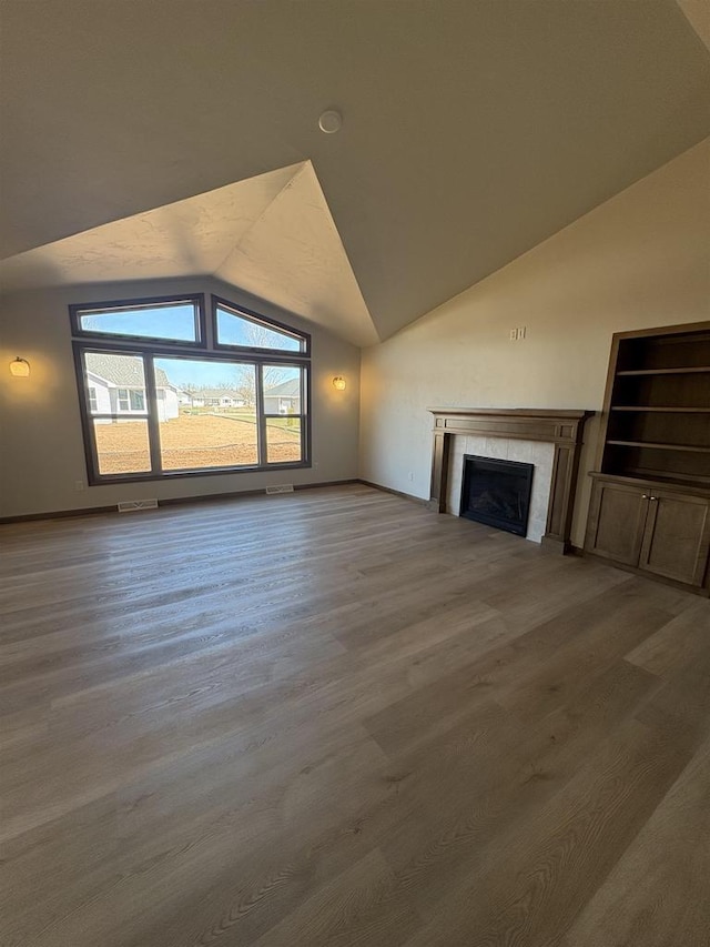 1354 Shelby Ln, De Pere, WI 54115 - unfurnished living room featuring lofted ceiling, a tiled fireplace, wood finished floors, and visible vents