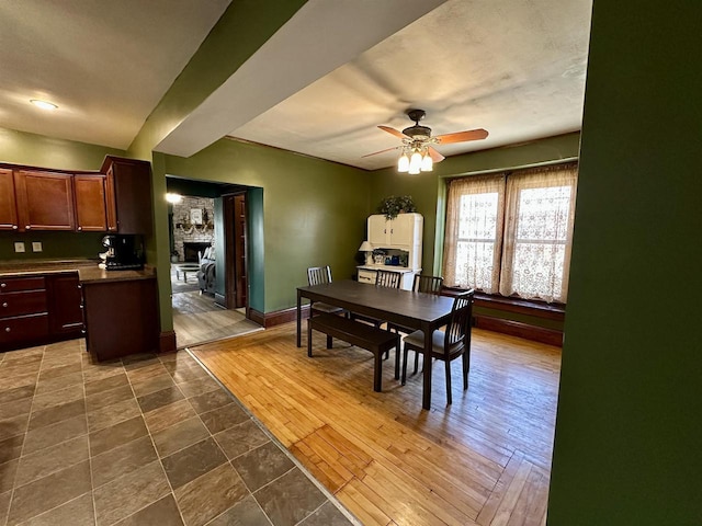 dining room with baseboards, ceiling fan, and a fireplace