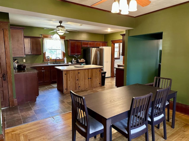 dining room featuring baseboards, ceiling fan, ornamental molding, and wood finished floors
