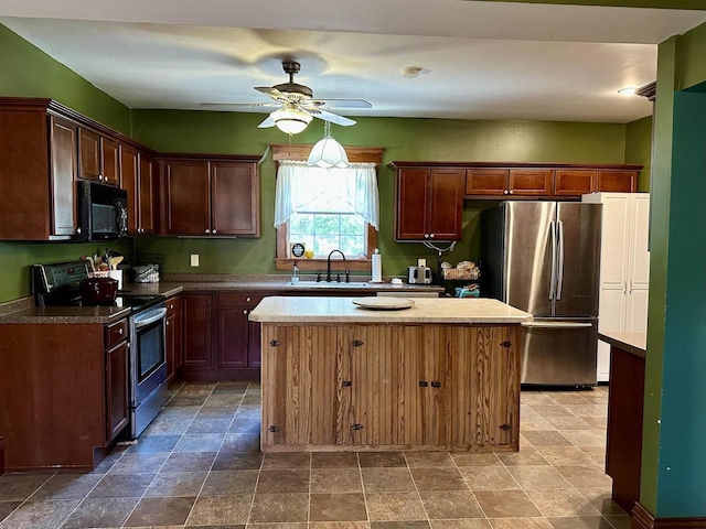 kitchen with a ceiling fan, appliances with stainless steel finishes, a sink, and a center island