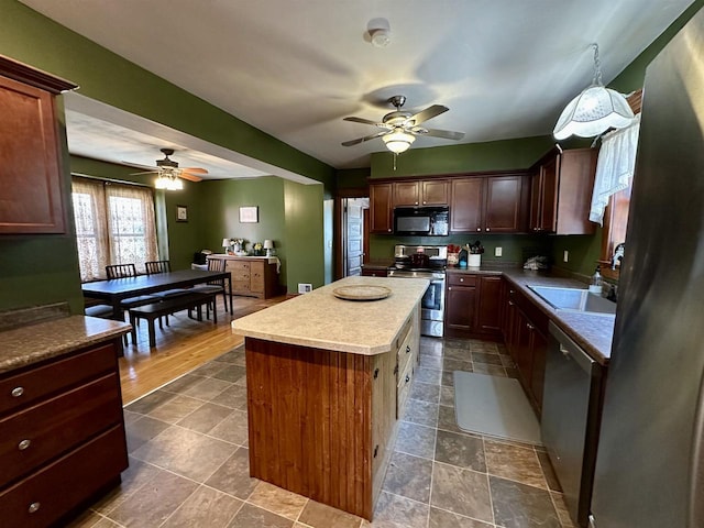 kitchen with a sink, ceiling fan, a kitchen island, and stainless steel appliances