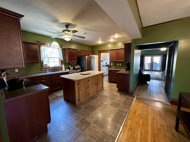 kitchen with ceiling fan, plenty of natural light, a center island, a sink, and freestanding refrigerator