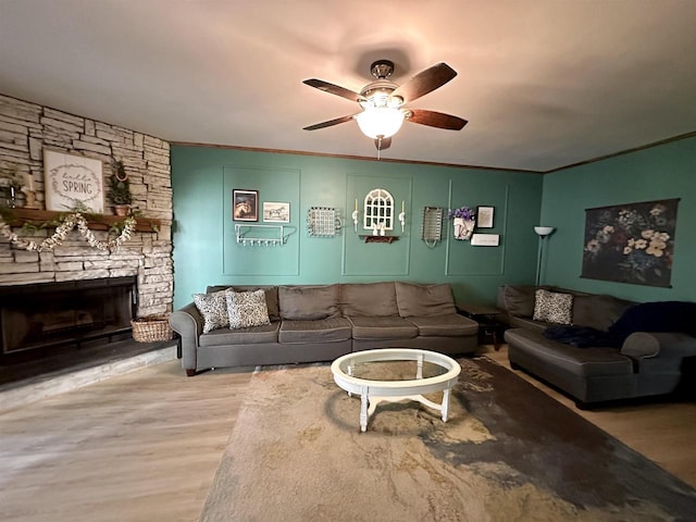living area with crown molding, ceiling fan, a fireplace, and wood finished floors