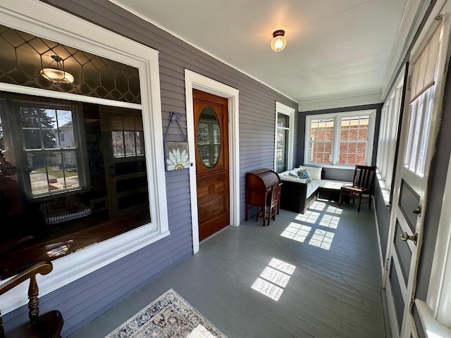 sunroom featuring wooden walls, ornamental molding, and wood finished floors