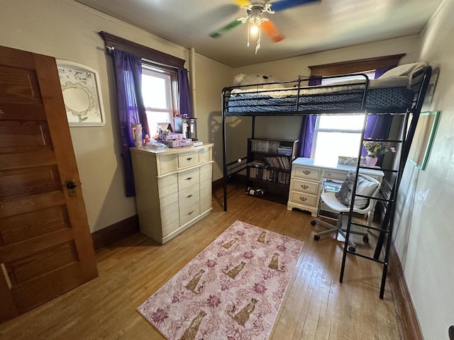 bedroom with baseboards, a baseboard heating unit, and wood finished floors