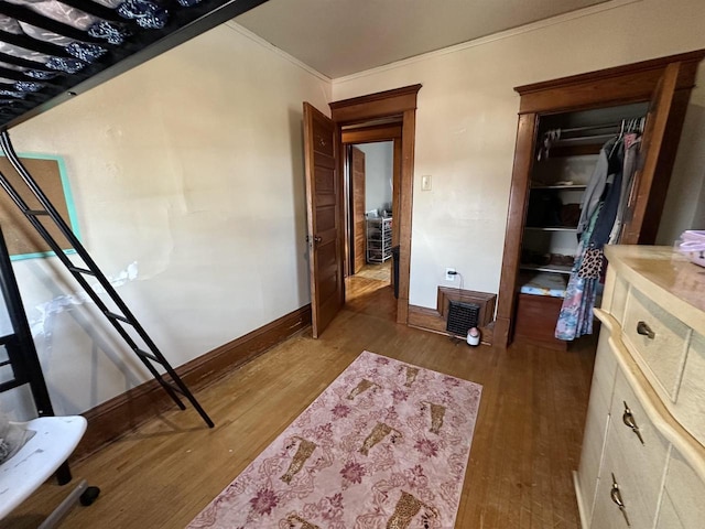 unfurnished bedroom featuring baseboards, ornamental molding, wood finished floors, and a closet