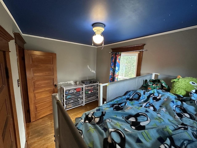 bedroom with crown molding and wood finished floors