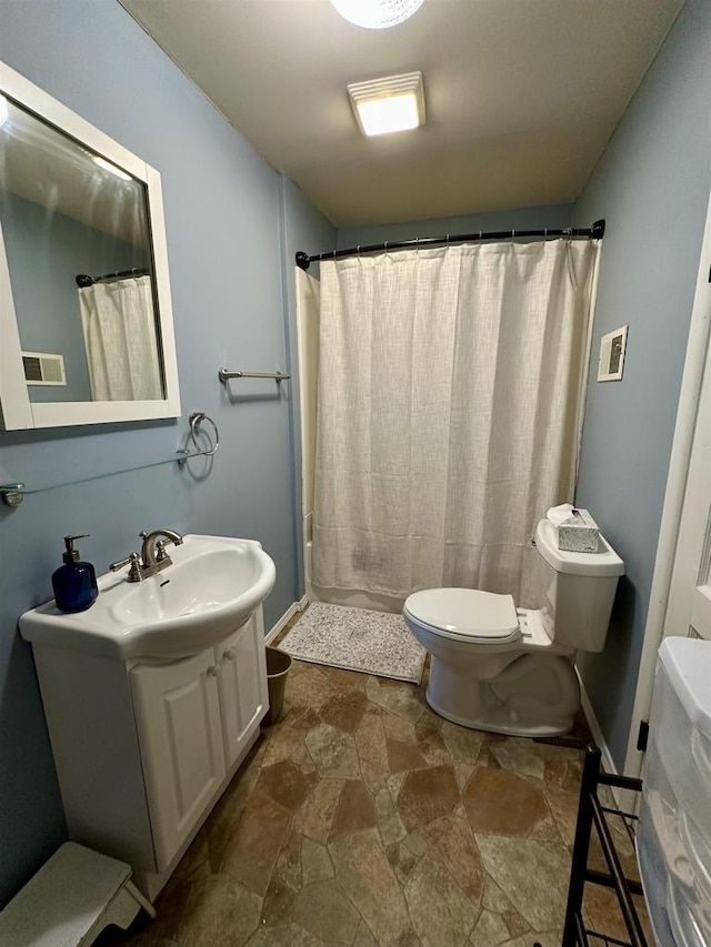 full bathroom with vanity, toilet, a shower with shower curtain, stone finish flooring, and visible vents