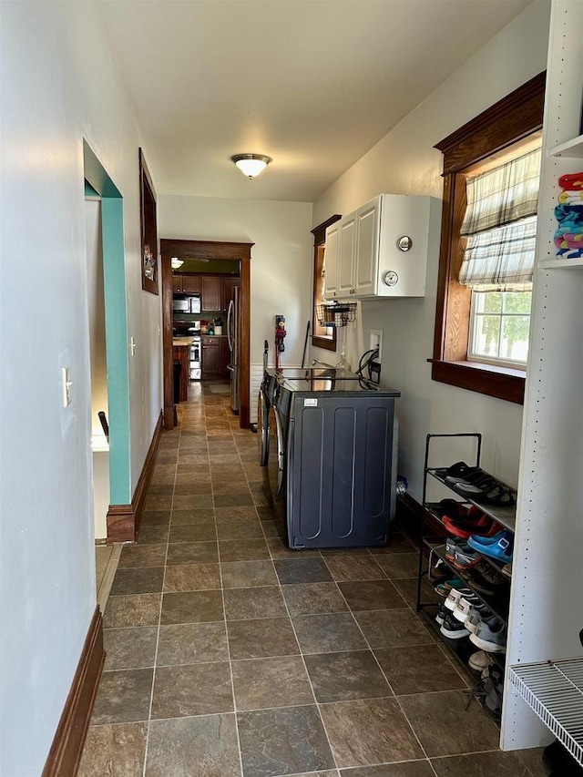 corridor with separate washer and dryer, baseboards, and stone finish flooring