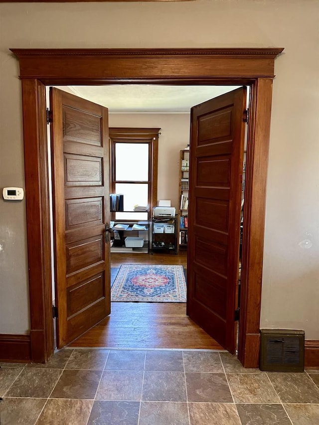 hallway with stone finish floor and baseboards