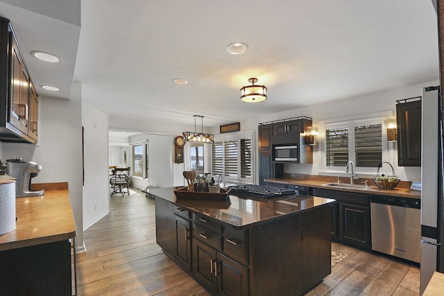 kitchen featuring gas cooktop, stainless steel dishwasher, a sink, recessed lighting, and wood-type flooring