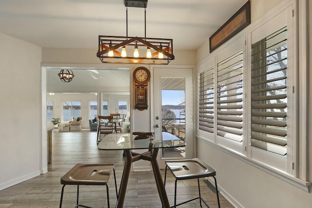 dining space featuring wood finished floors, baseboards, a wealth of natural light, and a notable chandelier
