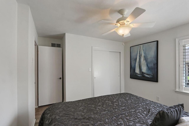 bedroom featuring ceiling fan, wood finished floors, visible vents, and a closet