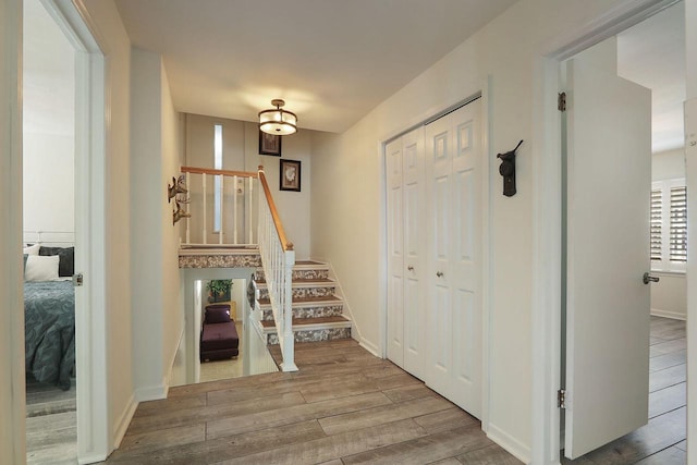 entryway featuring baseboards, wood finished floors, and stairs