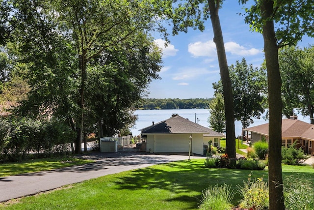 view of front facade featuring a garage, a water view, a front lawn, and aphalt driveway