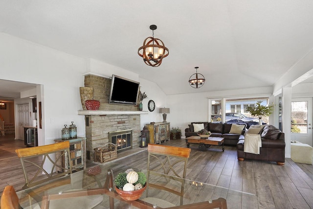 living room with a fireplace, a wealth of natural light, hardwood / wood-style flooring, and an inviting chandelier