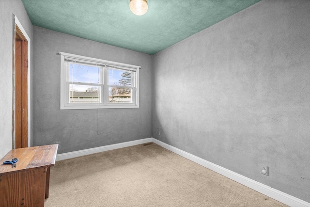 carpeted spare room featuring baseboards