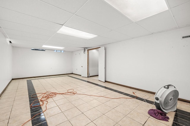 finished basement with visible vents, a drop ceiling, baseboards, and light tile patterned floors