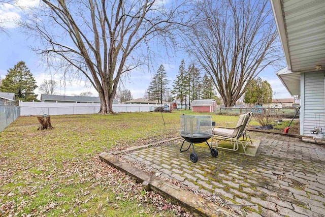 view of yard featuring a patio, a fenced backyard, an outdoor structure, and a shed
