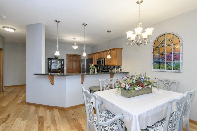 dining room featuring baseboards, a chandelier, and light wood-style flooring