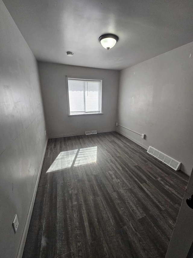 unfurnished room with wood finished floors, visible vents, and baseboards