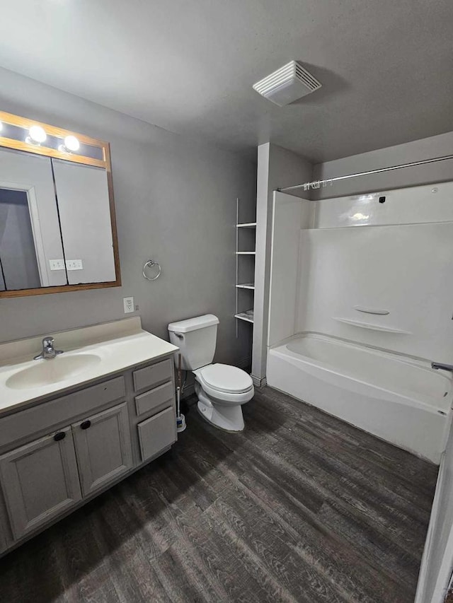 bathroom featuring wood finished floors, shower / bathing tub combination, vanity, toilet, and visible vents