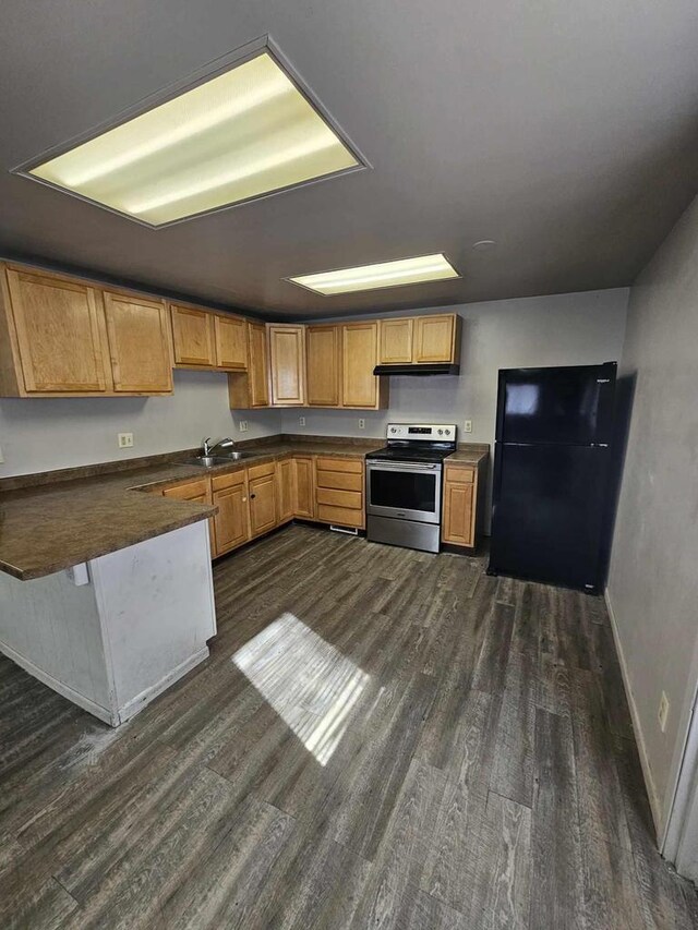 kitchen featuring dark countertops, freestanding refrigerator, dark wood-type flooring, and stainless steel range with electric stovetop