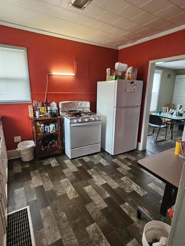 kitchen featuring ornamental molding, a healthy amount of sunlight, dark wood-type flooring, and white appliances