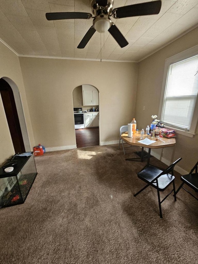 carpeted dining room featuring a ceiling fan, baseboards, arched walkways, and ornamental molding