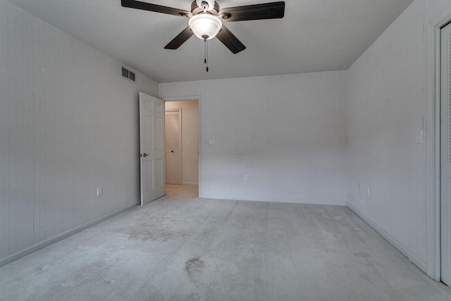 empty room with carpet, visible vents, and ceiling fan