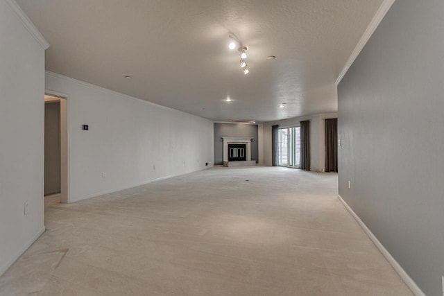 unfurnished living room featuring a textured ceiling, a glass covered fireplace, light colored carpet, baseboards, and ornamental molding