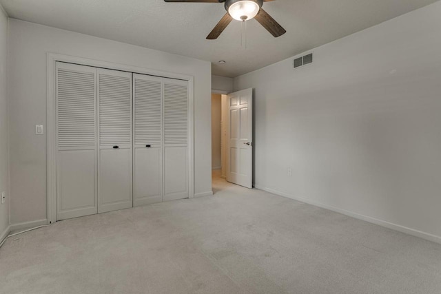 unfurnished bedroom with light carpet, baseboards, visible vents, a closet, and ceiling fan
