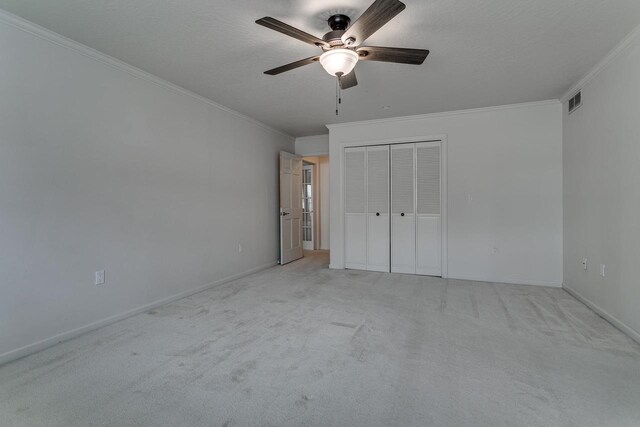 unfurnished bedroom with light colored carpet, ornamental molding, visible vents, and a closet