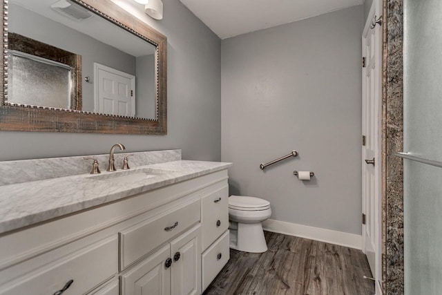 bathroom with toilet, baseboards, wood finished floors, a shower stall, and vanity