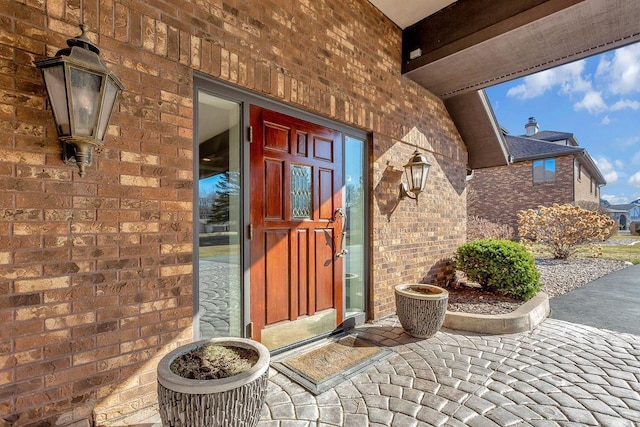 view of exterior entry featuring brick siding