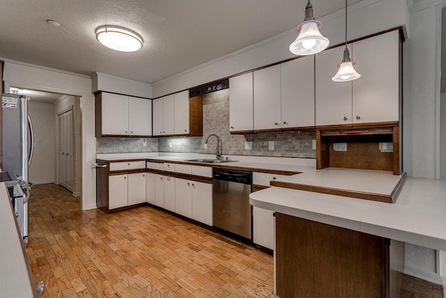 kitchen with stainless steel appliances, backsplash, light countertops, a sink, and white cabinetry