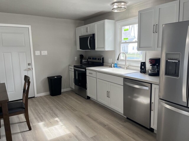 1610 S Oneida St, Green Bay, WI 54304 - kitchen featuring a sink, light wood-style floors, light countertops, white cabinets, and appliances with stainless steel finishes